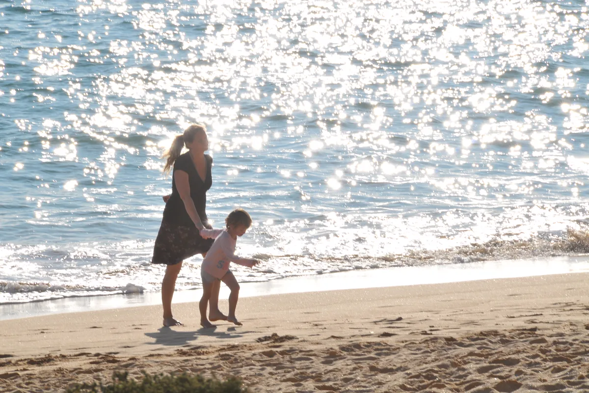 Mutter und Kind laufen gemeinsam am sonnigen Strand