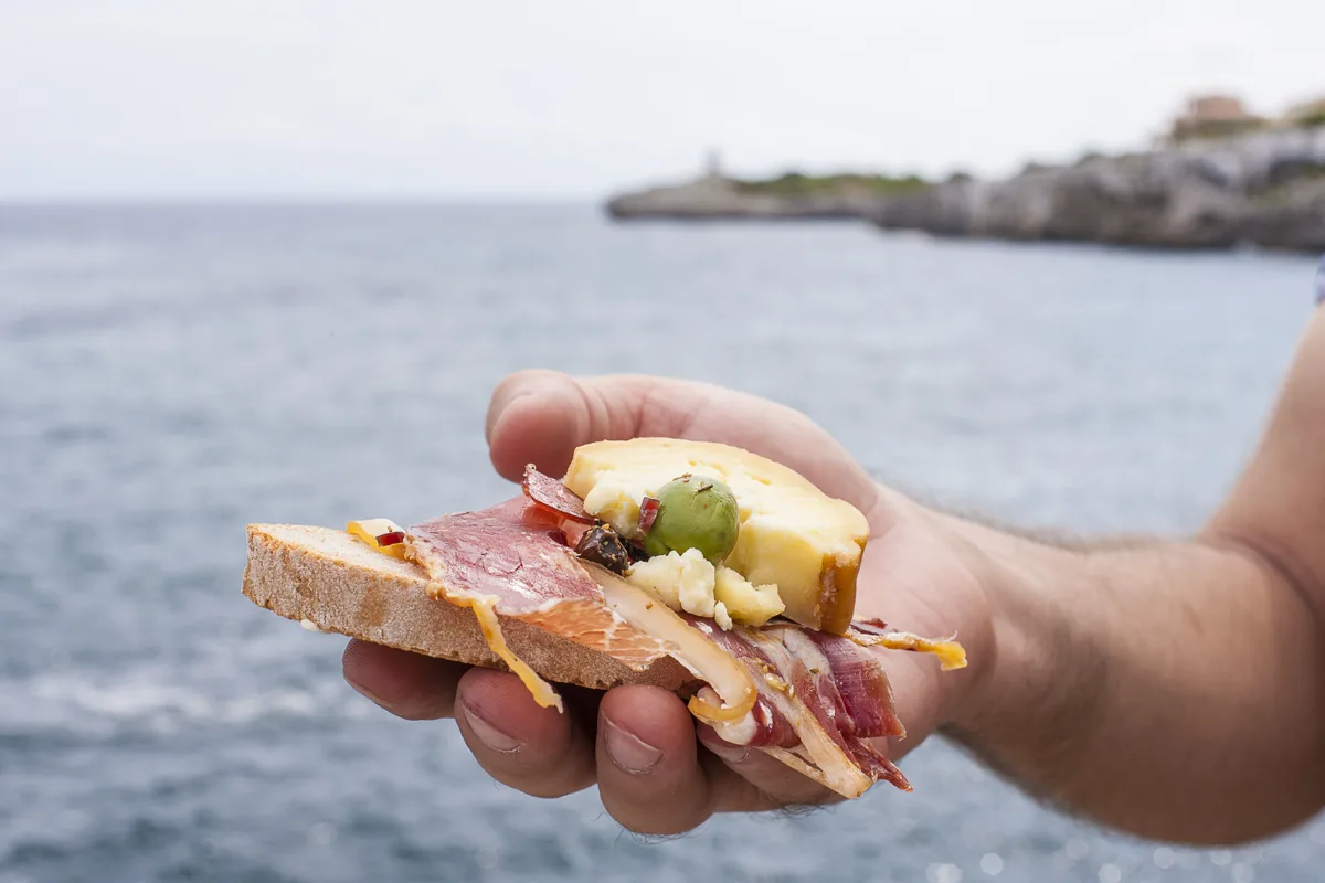 Brot mit Schinken, Käse und Oliven vor der Küste Mallorcas
